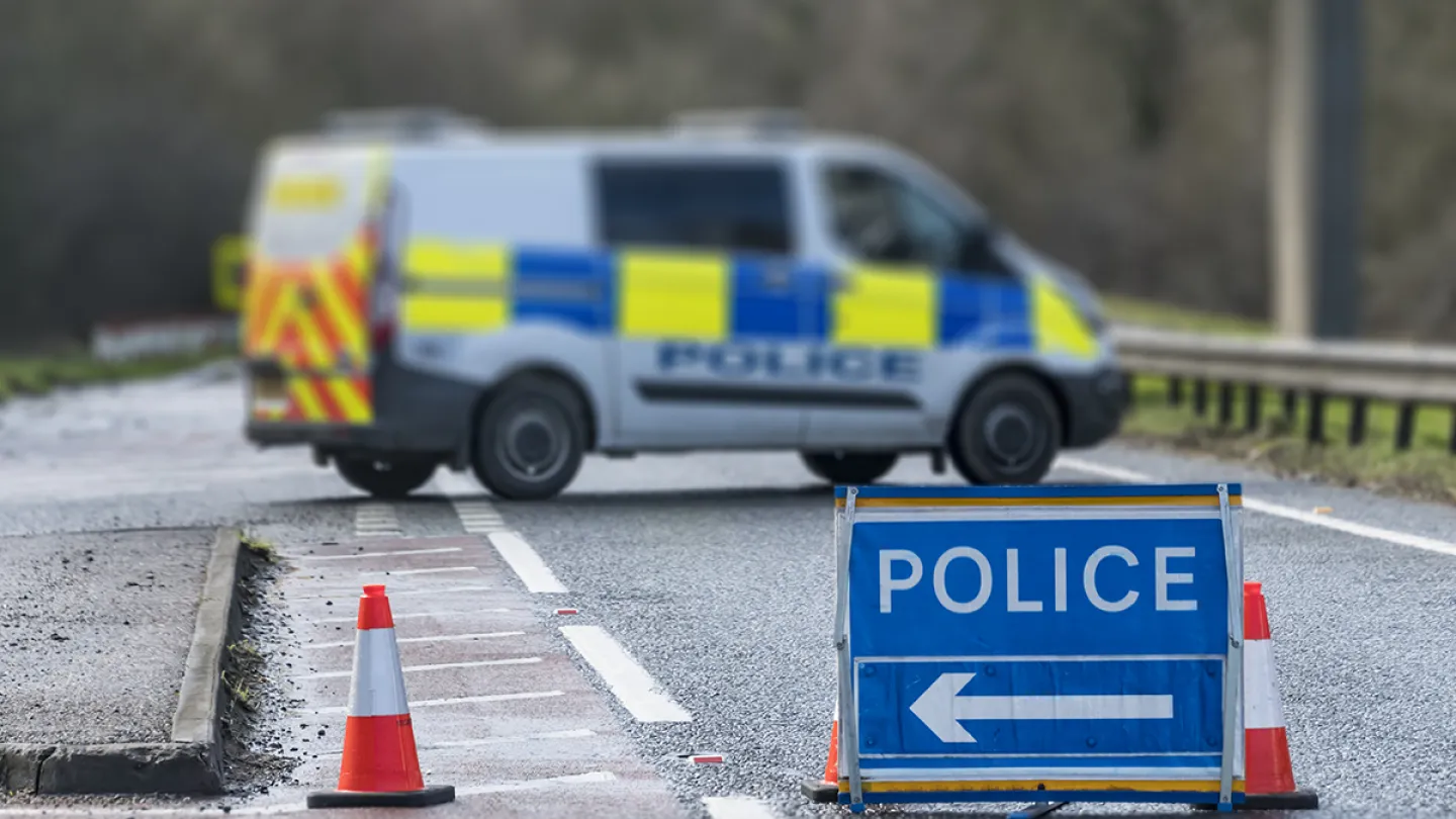 Police van blocking a road with cones and a diversion sign at a collision scene