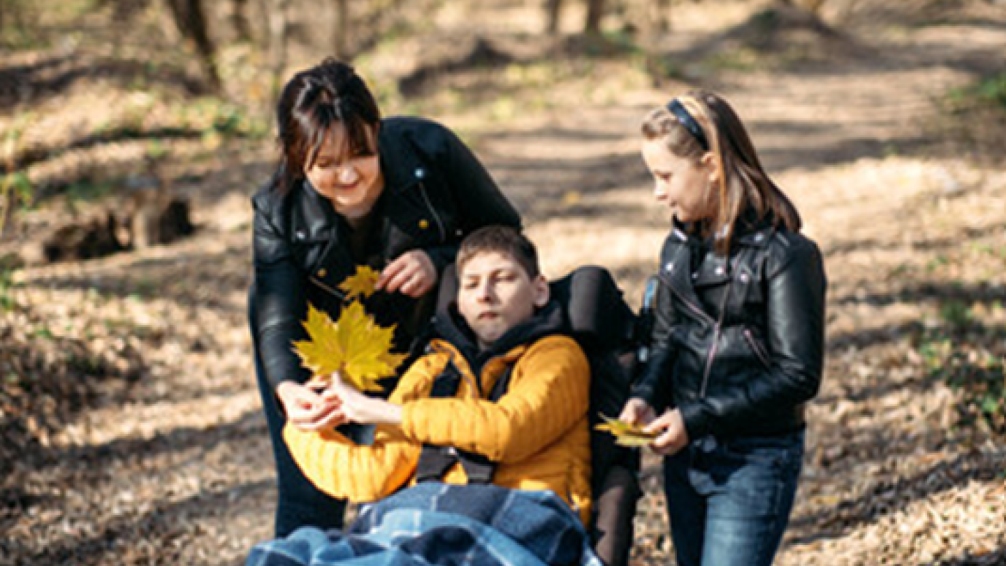 Boy in wheelchair with mom and sister in forest 