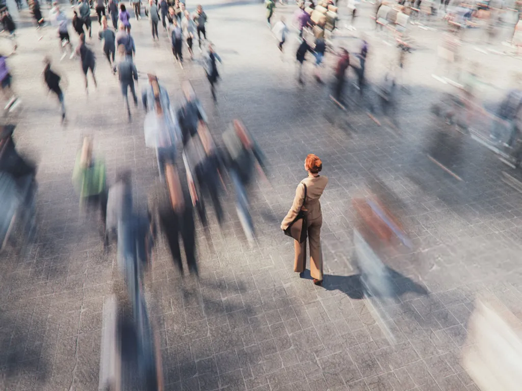 Person standing still in a busy crowd with people moving past in motion blur