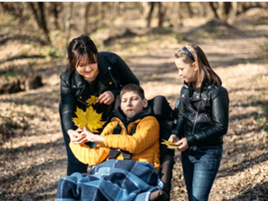 Boy in wheelchair with mom and sister in forest 